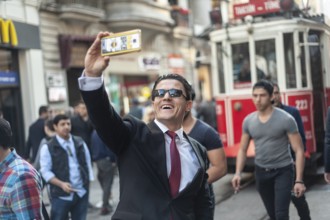 Istiklal Street, Istanbul, Turkey. March 27th 2016 A man in a business suit poses for a selfie in