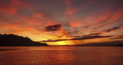 A breathtaking sunset over Lake Geneva, illuminated with vibrant shades of orange and red, with the