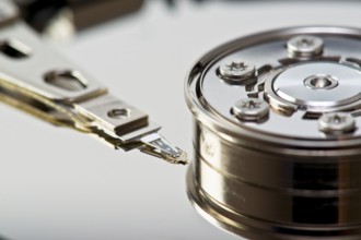 A detailed close-up image showing the read-write arm of a hard drive in precise detail, positioned