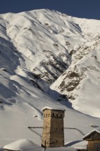 A stone tower stands amid a stunning snowy mountain landscape in Georgia The scene highlights the