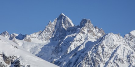 Majestic snow-covered mountain peaks rise against a clear blue sky, capturing the breathtaking