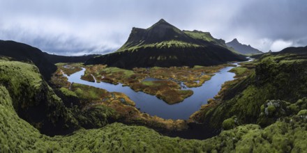 A stunning panoramic view of a moss-covered volcanic mountain with a winding river and colorful