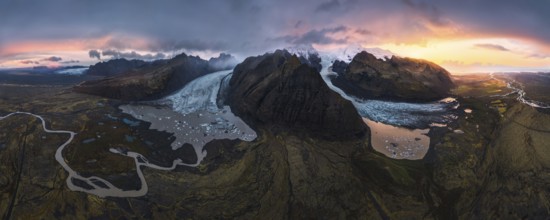 A stunning aerial view of a glacier cascading between volcanic mountains, surrounded by glacial