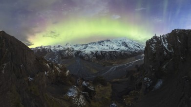 Breathtaking view of the Northern Lights illuminating the sky above a snow-covered mountain range