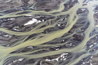 Stunning aerial capture of Iceland's golden rivers, gracefully weaving through patches of snow,