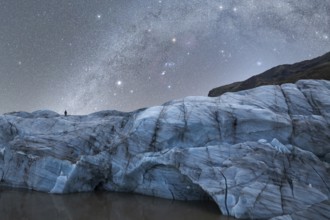A lone figure stands atop a majestic glacier in Iceland The night sky is filled with a breathtaking