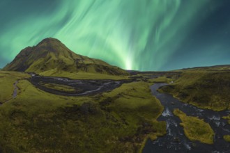Majestic Northern Lights dance in the sky above a vibrant green valley in Iceland, with a