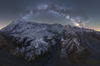 Stunning view of Icelandic mountains blanketed in snow, illuminated by a dazzling starry night sky