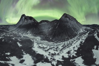 Awe-inspiring aurora borealis dances in the night sky above snow-dusted mountains and rugged