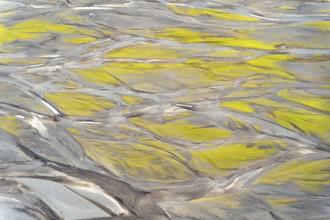 Aerial view showcasing intricate textures and patterns created by vibrant Icelandic rivers. Natural