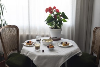 Warmly lit coffee table covered in a white cloth, featuring various desserts like cherry-topped