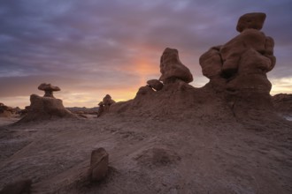 Unique sandstone formations at sunrise in Goblin Valley State Park, Utah. The sky casts a warm glow