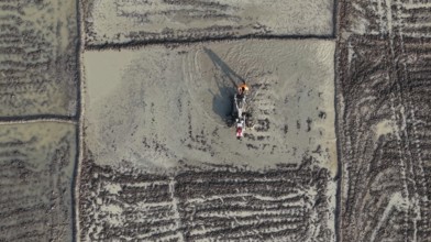 In an aerial view, a farmer ploughs a rice paddy field with a power tiller on February 16, 2026 in
