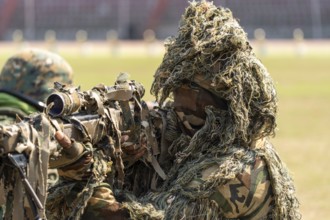 A camouflaged sniper of the Central Reserve Police Force takes aim during a tactical demonstration