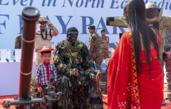 A child poses for a photograph beside a CRPF commando in full camouflage gear during a public