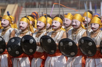 Artists in traditional attire perform a cultural martial dance with swords and shields during the