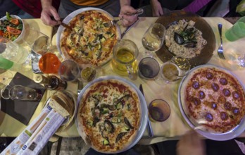 Different pizzas and mussel dishes on a table in a restaurant, Italy