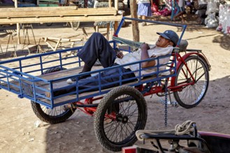 A man resting on a cart in a sunny market environment, The market in the streets of Nasca in Peru
