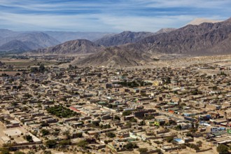 A panoramic view of a city against a backdrop of mountains and clear skies, the city of Nasca in