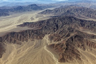 Winding hills and a dry riverbed in an impressive, dry landscape with shades of brown colors, The