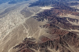 Extensive desert landscape and mountains with many shades of brown and ochre, a dried-out riverbed