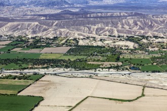 Extensive green areas and riverbed with mountain ranges on the horizon, the desert landscape near
