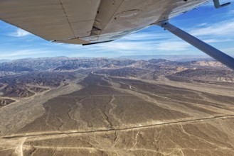 View from an airplane of a dry desert landscape with mountains and blue sky, The desert landscape