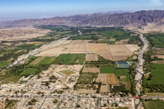 View of fields and cityscape along a river and mountains in the background, The desert landscape