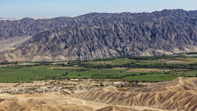 Green areas with trees and fields against a majestic mountain backdrop, the desert landscape near