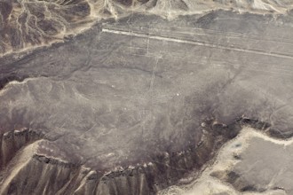 A pictogram surrounded by geoglyph lines in a sandy desert area, viewed from the air with