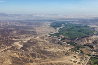 Wide desert-like landscape with a narrow green river valley in the foreground, the desert landscape