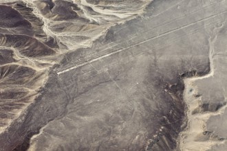 Geoglyphs and lines visible through the air that criss-cross a sandy desert landscape with
