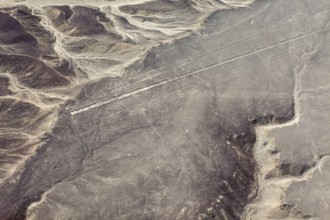 Lines and geoglyphs over an infinite desert plain, taken from lofty heights, with mountain slopes,