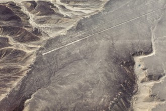 Lines and geoglyphs visible from the air in a desert-like environment surrounded by mountains, The