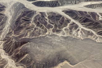 Aerial view of a mountainous desert landscape with visible eroded patterns next to Nazca lines, the