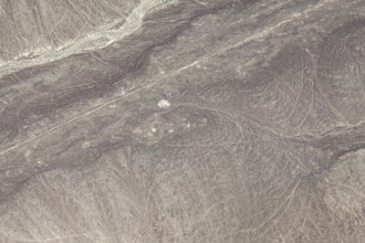 Aerial view of line patterns in a dry, sandy desert landscape, the geoglyphs and images in the