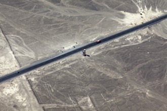 Aerial view of a dry environment with Nazca lines and a parallel road, The geoglyphs and images in
