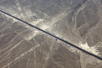 Aerial view of a road running through a desert landscape with lines, the geoglyphs and images in