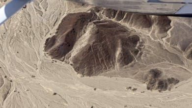 Aerial view of a desert landscape with geoglyphs and sandy hills, the geoglyphs and images in the