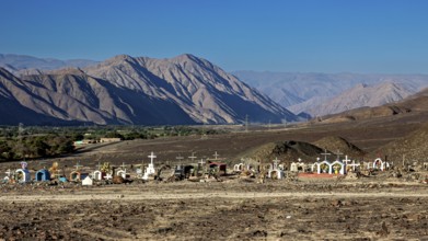 Cemetery under clear blue sky in barren desert landscape near mountains, cemetery in the Nazca