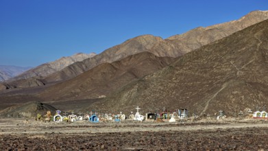 Cemetery in a desert-like landscape in front of a mountain range under clear skies, cemetery in the