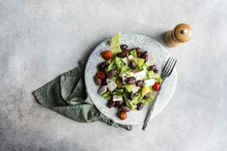 A vibrant Greek salad featuring tomatoes, lettuce, red olives, olive oil, and feta cheese