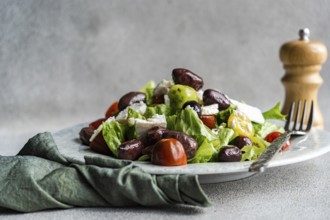 A vibrant Greek salad featuring tomatoes, lettuce, and red olives, topped with feta cheese and