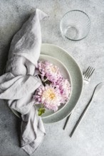 A serene table setting featuring delicate chrysanthemum flowers resting on stacked plates,