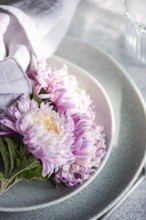 A close-up of pink chrysanthemums on a set table with pastel linen, evoking a serene and elegant