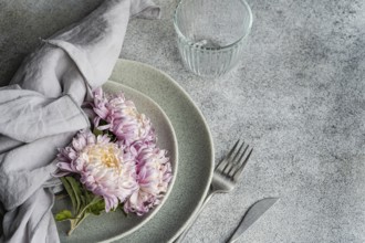 A soft, rustic dining setup features pink and cream chrysanthemums on ceramic plates with a linen