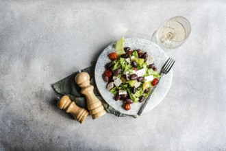 A vibrant Greek salad with tomatoes, lettuce, fermented olives, feta cheese, and olive oil