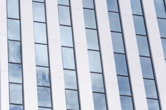 A detailed view of a modern building featuring a rhythmic pattern of white and glass vertical