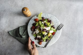 A vibrant Greek salad featuring tomatoes, lettuce, fermented olives, and feta cheese