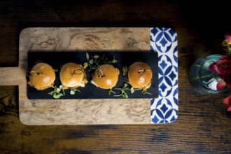 Top-down view of four gourmet pulled pork and cabbage mini burgers served on a black slate board